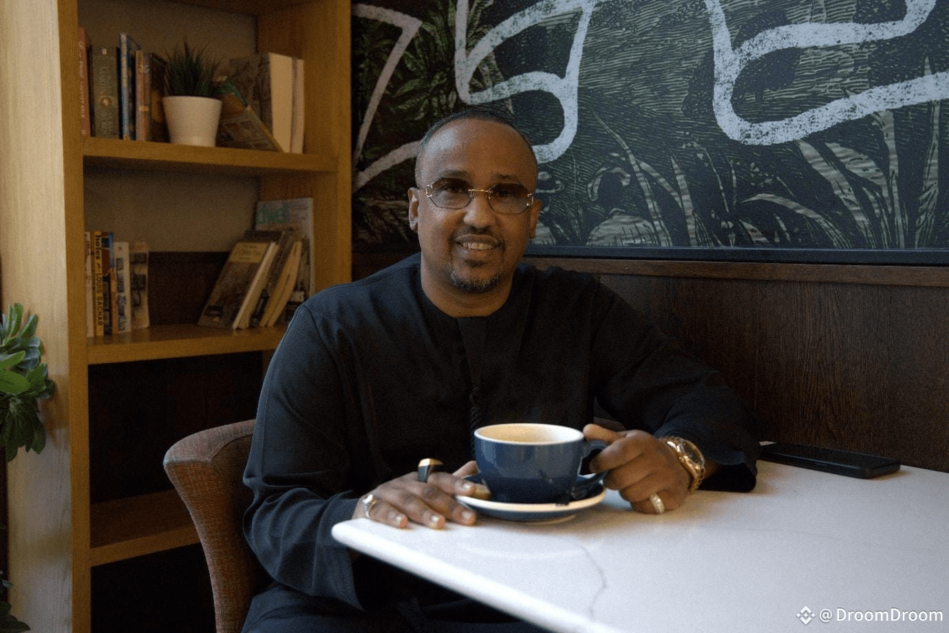 A person sitting at a table with a cup of coffee<br /><br />AI-generated content may be incorrect.
